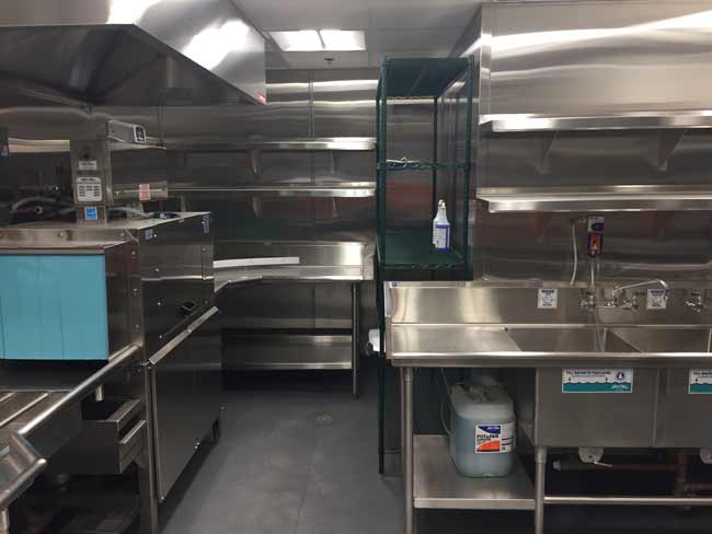 Full custom back of house in restaurant with stainless wall flashing, dish tables wall shelves